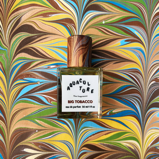 Perfume bottle labeled 'Aquaculture Big Tobacco' on a multicolored marbled background
